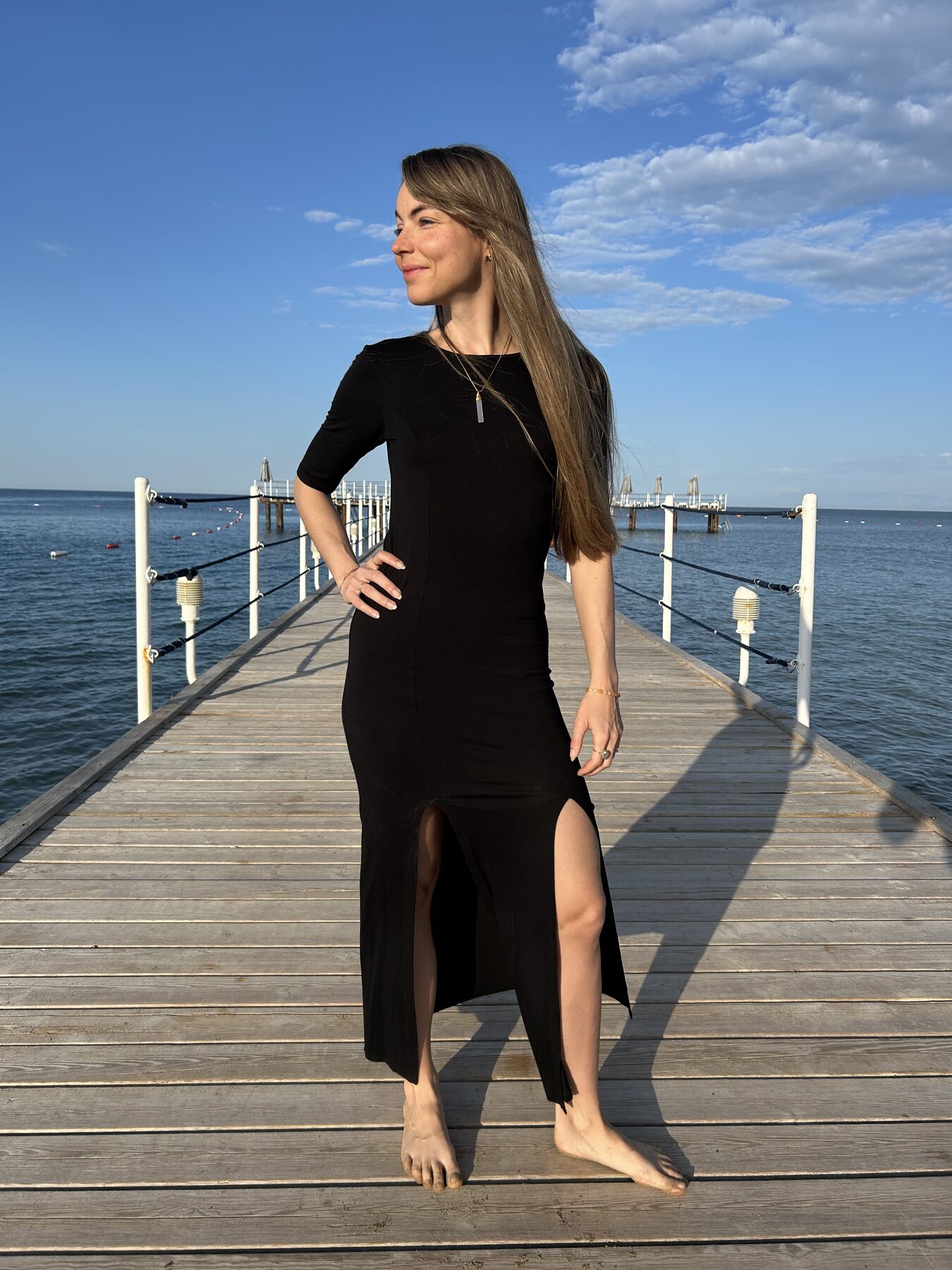 Coach in black dress on a pier, eyes closed, breathing into the sea